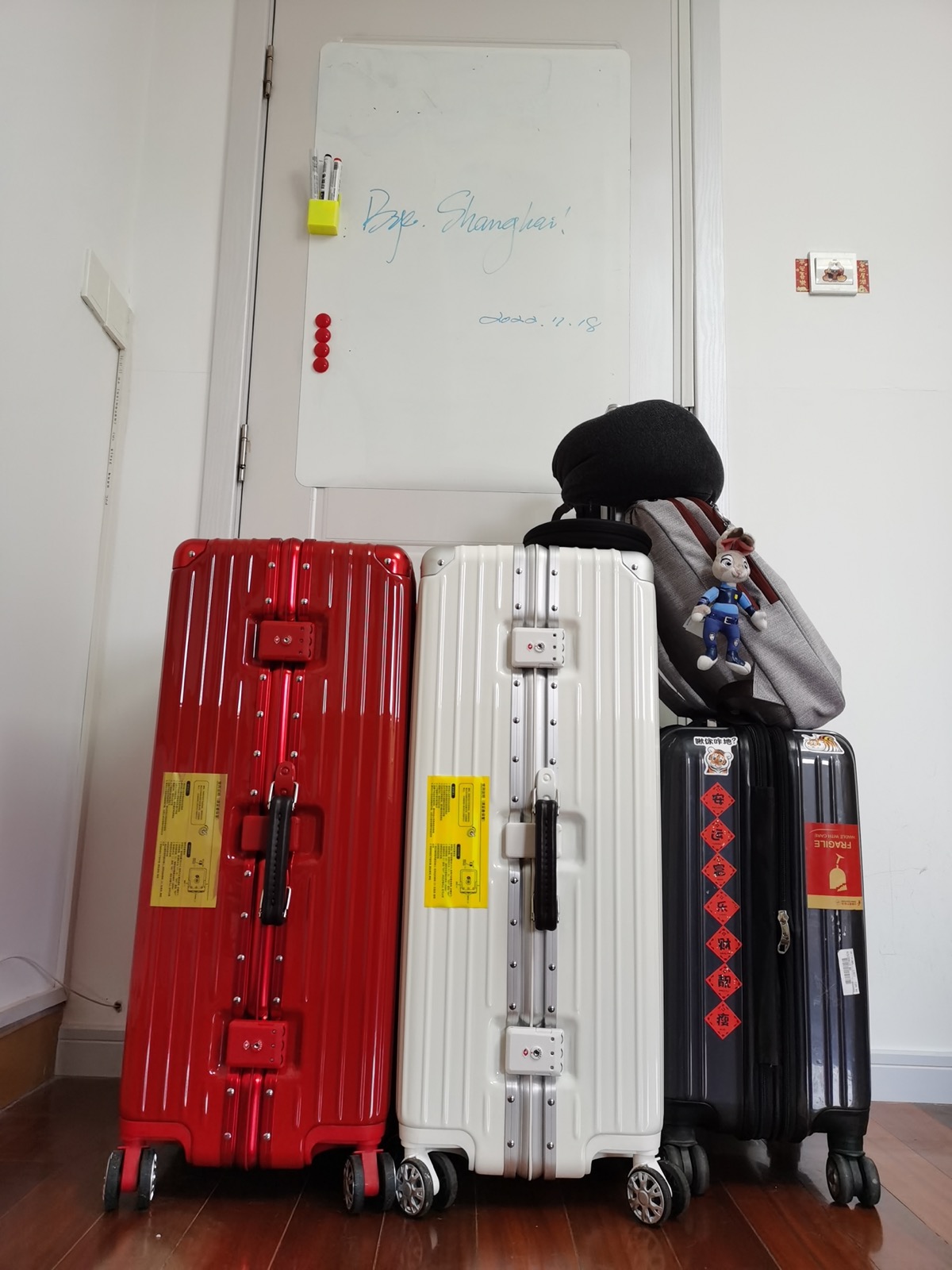 Three suitcases against a wall, whiteboard behind them reads Bye. Shanghai! 2022.11.18
