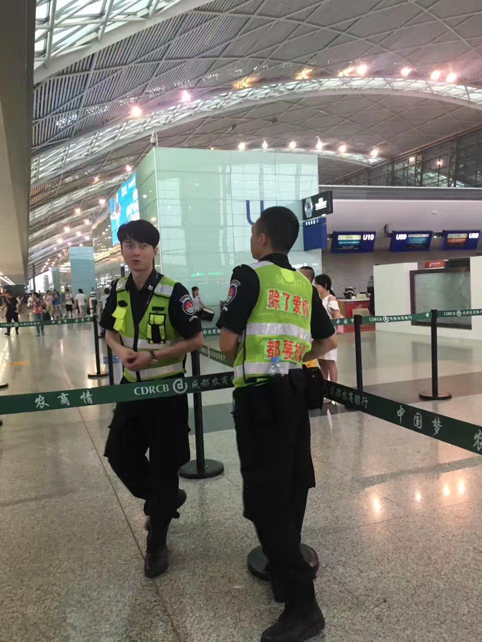 Airport security guard with vest reading 'Except for love, everyone must queue', Chengdu