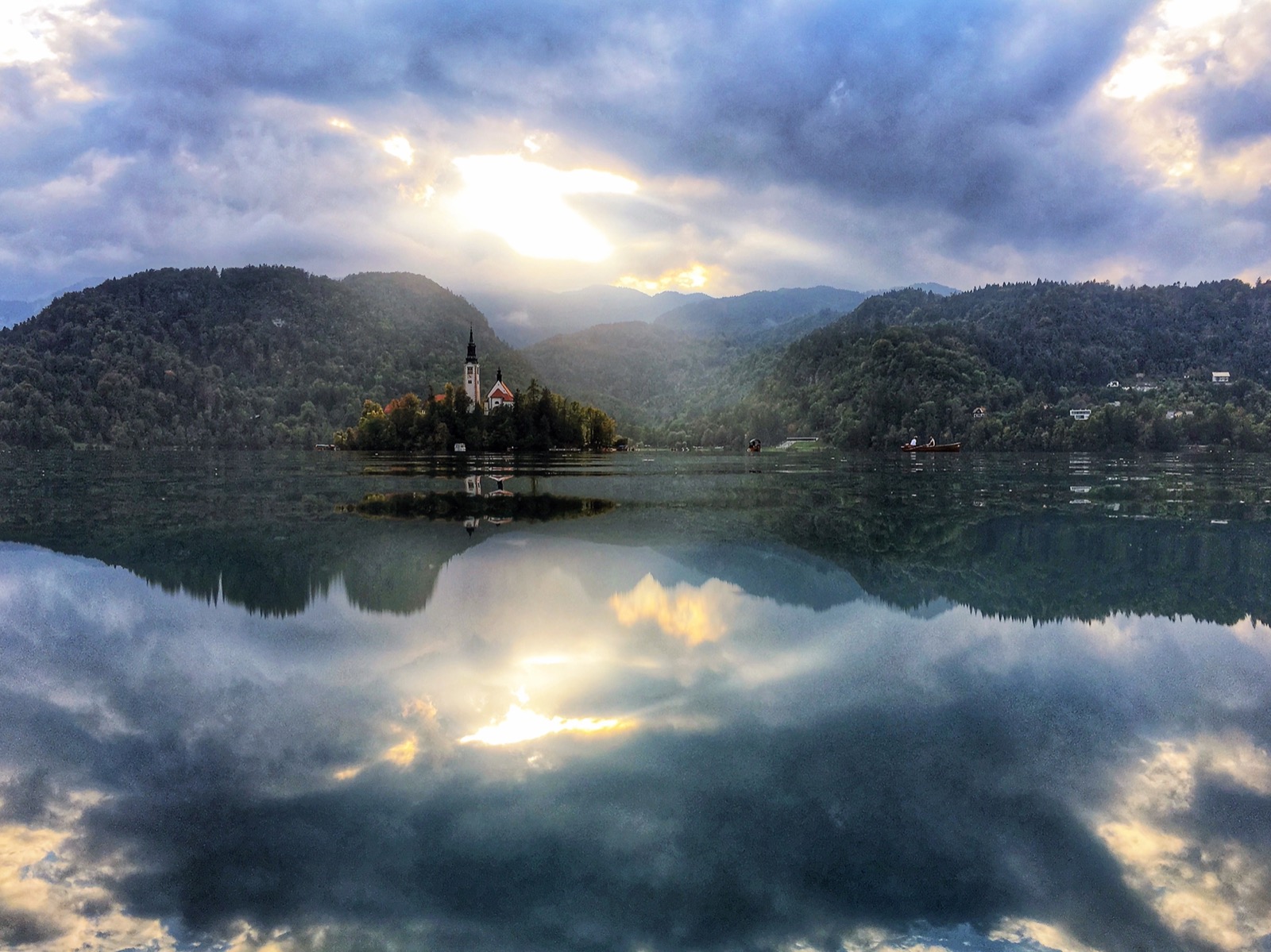 Lake Bled, Slovenia — island church reflected perfectly in still water under a dramatic sky