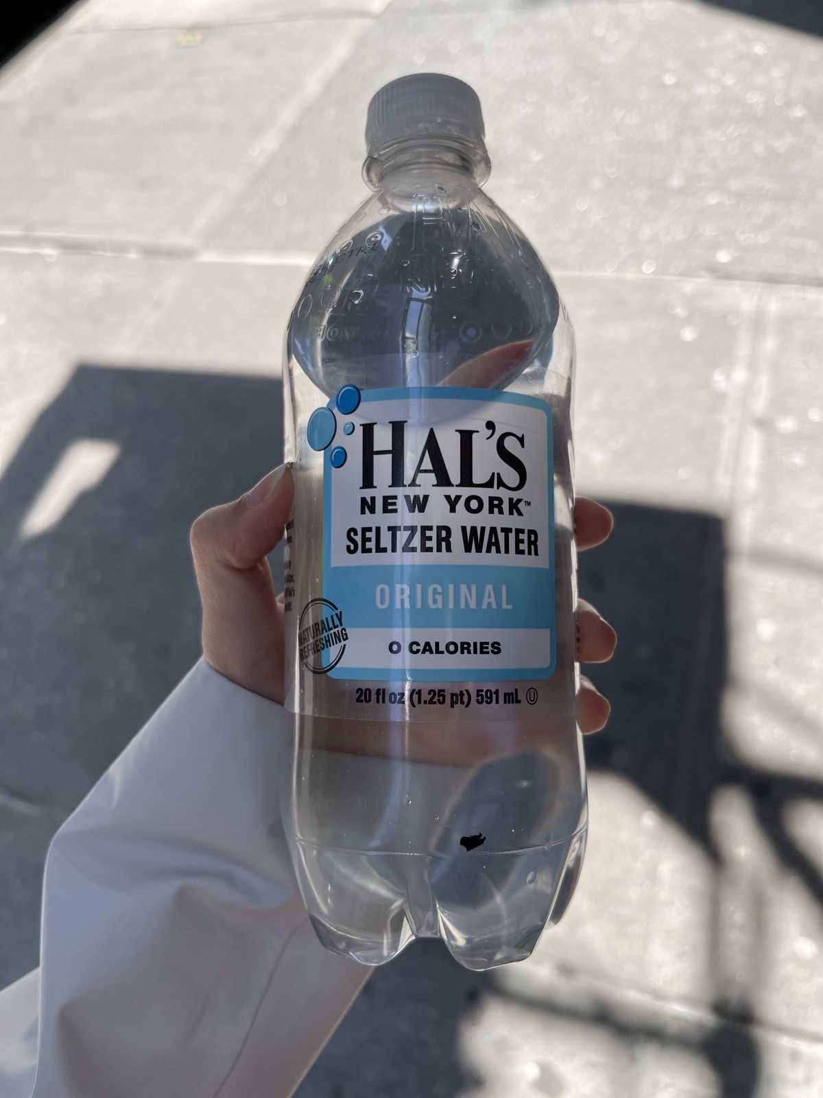 A bottle of Hal's New York Seltzer Water held up outside the Met